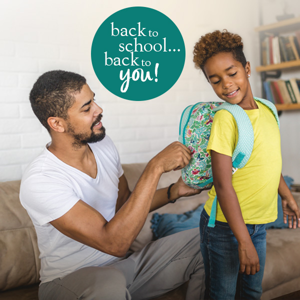 Young man zipping up his son's backpack. Blue sticker reads: Back to school... back to you!