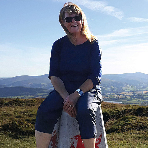 Jacque Jones, dressed in a blue t-shirt and trousers, sitting on top of a concrete podium on the Brecon Beacons